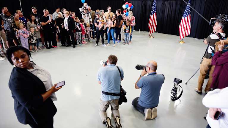 Valokuvaajat kuvaavat ihmisryhmää lentoasemalla.