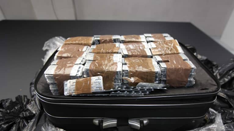 Matkalaukuun pakattuja huumausainepusseja.