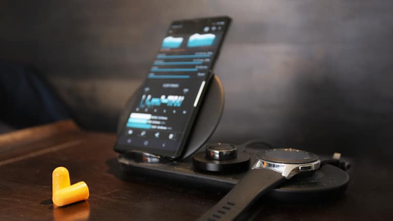 Yöpöydällä kännykkä, älykello, älysormus ja keltaiset korvatulpat.