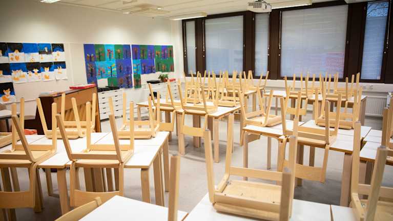 Luokkahuone jossa tuolit nostettu pöydille