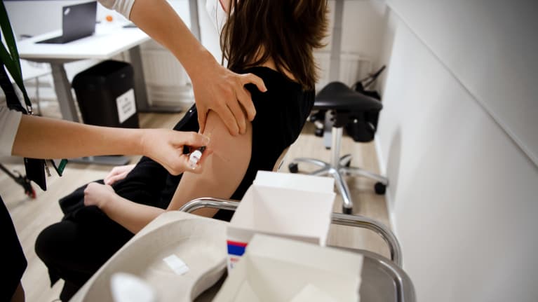 Hoitaja pistää rokotetta olkavarteen.