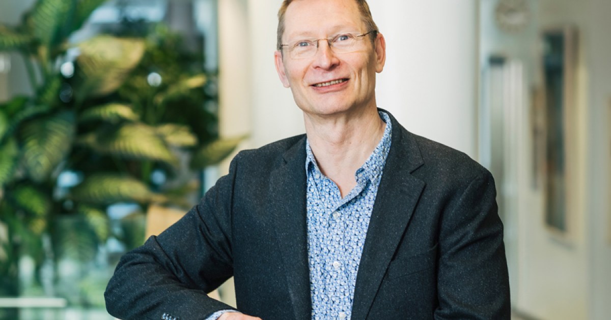 Anssi Auvinen katsoo kameraan, taustalla huonekasveja.