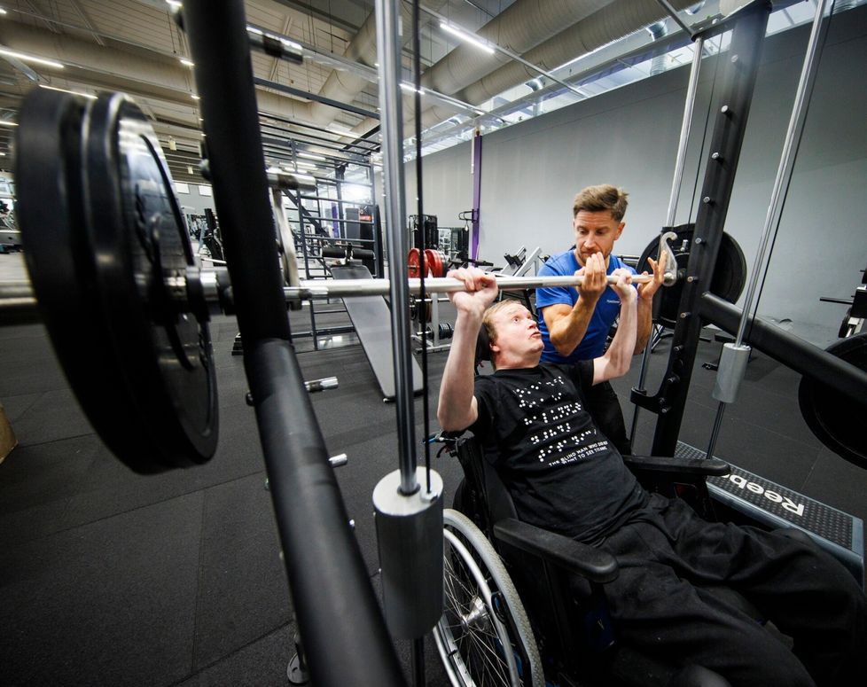 Fysioterapeutti Iiro Teittinen huolehtii siitä, että esimerkiksi penkkipunnerrus sujuu turvallisesti. – Työntövaiheessa varmistan kevyesti ja jarruttamisvaiheessa on pidettävä tangosta kiinni. Petri tekee kuitenkin 90-prosenttisesti itsellistä työtä.