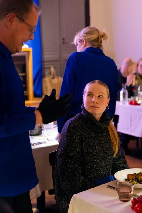 Tarjoilija selostaa Kiia Kalmille pääruoan sisältöä.