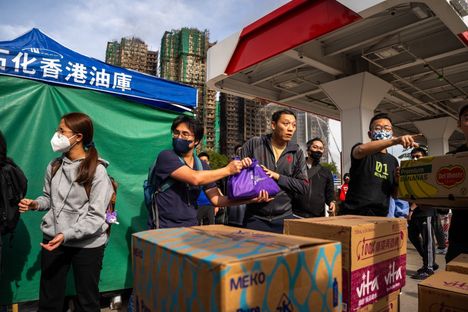 Vapaaehtoiset muodostivat ihmisketjun lahjoitettujen avustustarvikkeiden siirtämiseen Tai Pon alueella torstaina. Palaneet rakennukset näkyvät taustalla.
