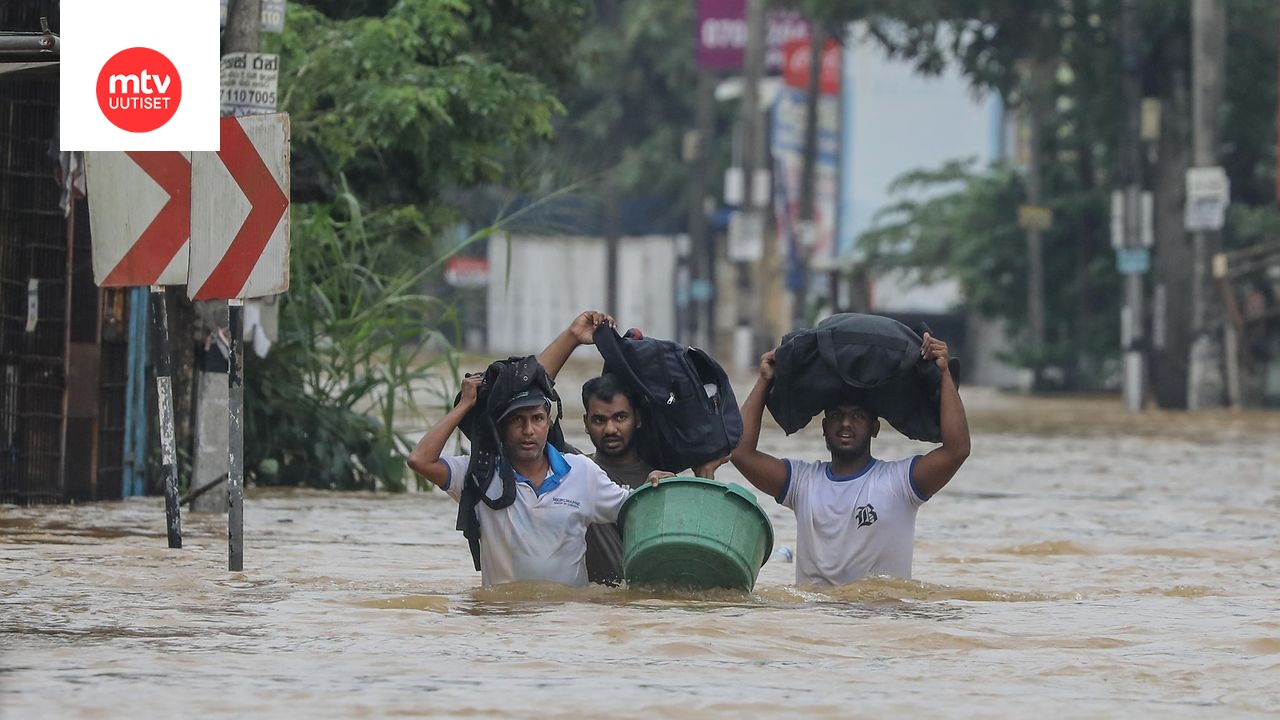 Tulvien uhrit kahlaavat tulvineella tiellä rankkasateen aikana Colombon esikaupungissa Sri Lankassa 29. marraskuuta 2025.
