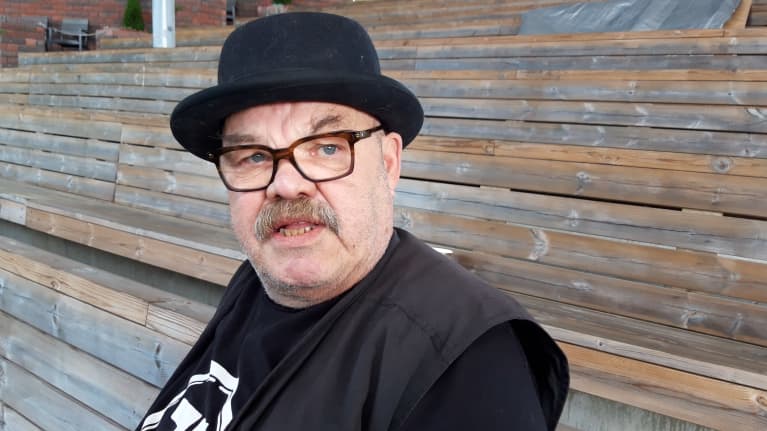 Jaakko Teppo istuu tyhjän kesäteatterin katsomossa knallihattu päässään.