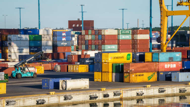 Eri värisiä merikontteja satamassa.