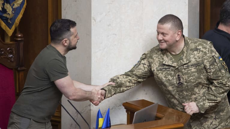 Puhujankorokkeella istuva Volodymy Zelenskyi kättelee Valeri Zalužnyita.