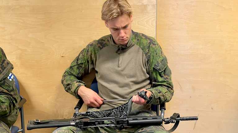 Varusmies puhdistaa asettaan.