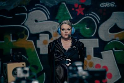 Nainen graffitiluolassa headset-kuulokkeet päässä. Hän on näyttelijä Elina Knihtilä elokuvassa Peluri.