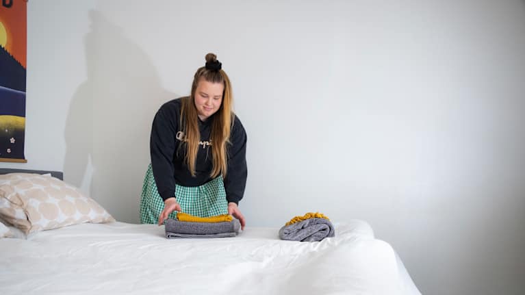 Nainen petaa sänkyä.