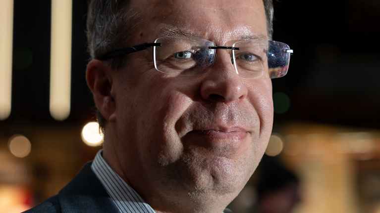 Pukuun pukeutunut mies katsoo kameraan kauppakeskuksessa.