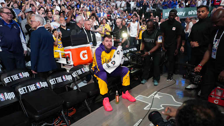 Luka Doncic istuu penkillä ympärillään median edustajia ja takanaan yleisöä.