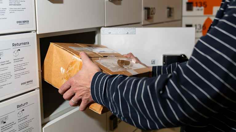 Anonyymi mies ottamassa pakettia automaatista.