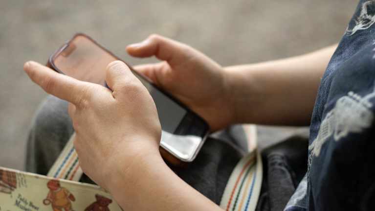 Lähikuva henkilöstä, joka käyttää älypuhelinta.