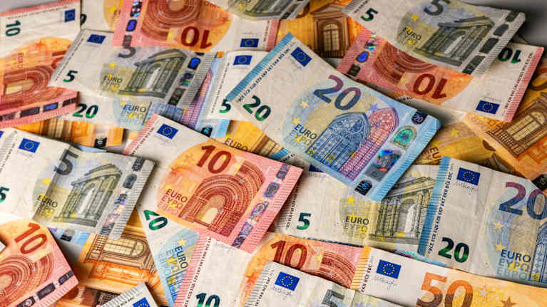 Erikokoisia ja arvoisia euroseteleitä levitettynä sekaisin pöydälle.