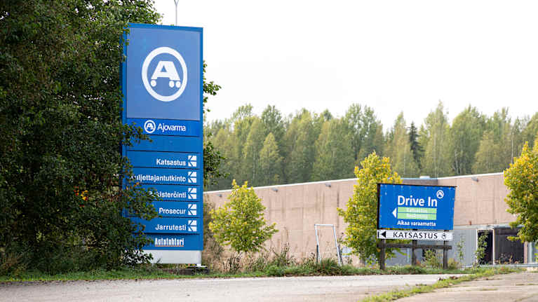 Kuvassa on Ajovarma-katsastusaseman piha-alue ja kaksi opastetta.