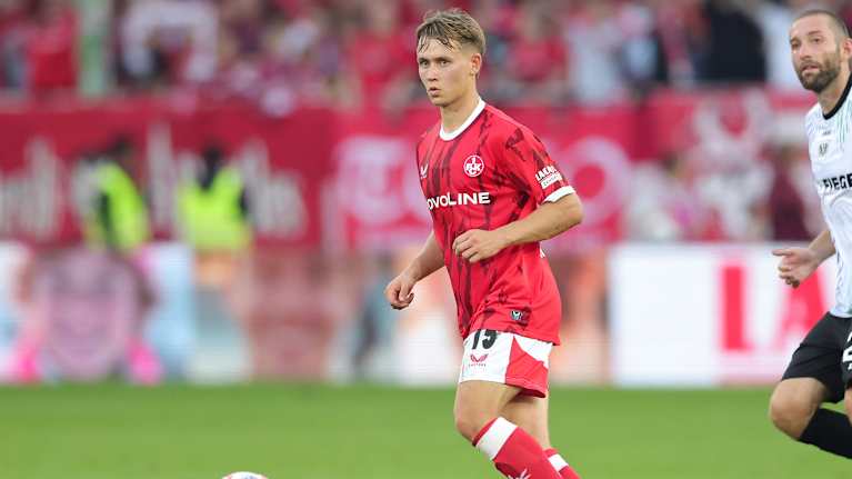 Naatan Skyttä seuraa jalkapallokentällä omien pelaajiensa liikkeitä, pallo jaloissaan.