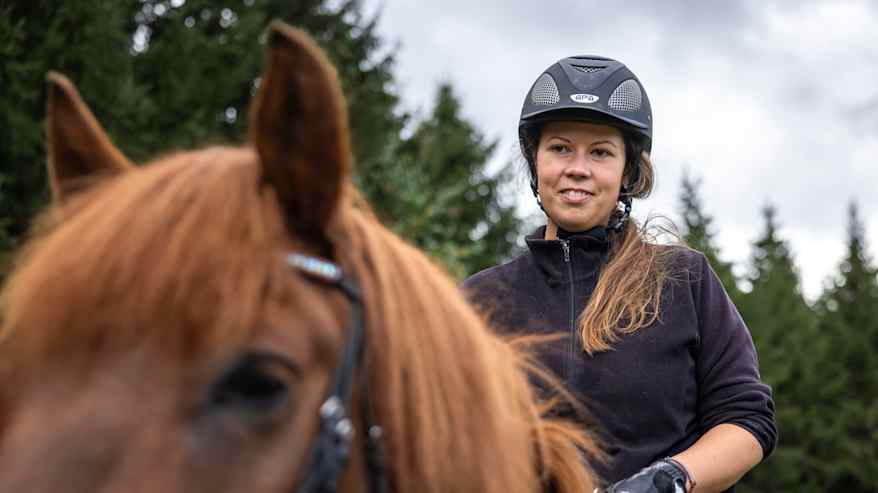 Nainen ratsastaa hevosella.