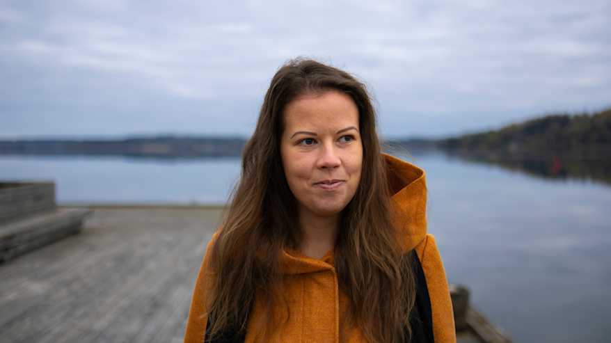 Nainen hymyilee laiturilla kävellessään.