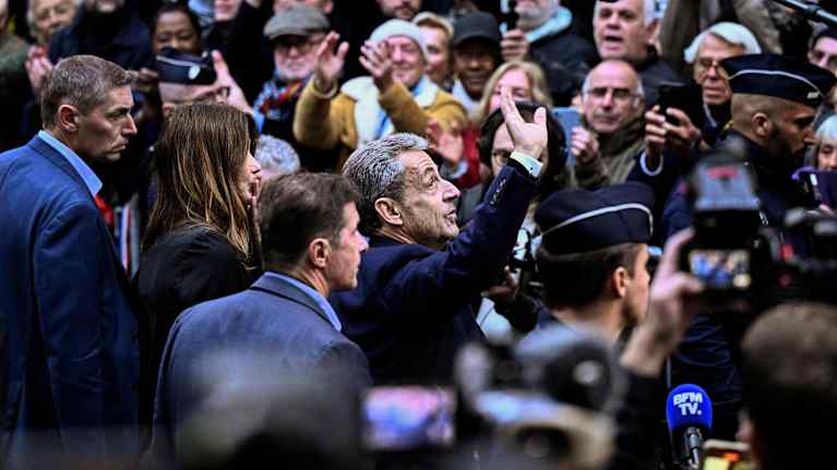 Nicolas Sarkozy vilkuttaa ihmisten keskellä.