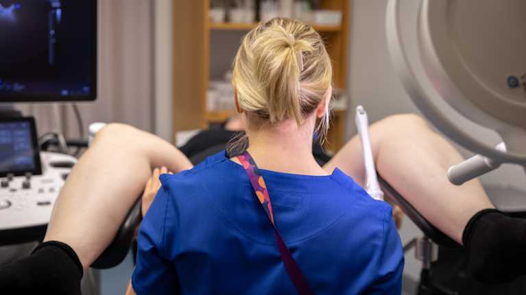 Gynekologi suorittamassa ultraäänitutkimusta potilaalle sairaalassa. Kuva on otettu lääkärin selän takaa.