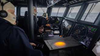 Suojahuppupäiset sotilaat tarkkaileva tilannetta laivan komentosillalla.