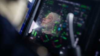 Suojahuppupäinen naissotilas heijastuu tutkanäytöltä.