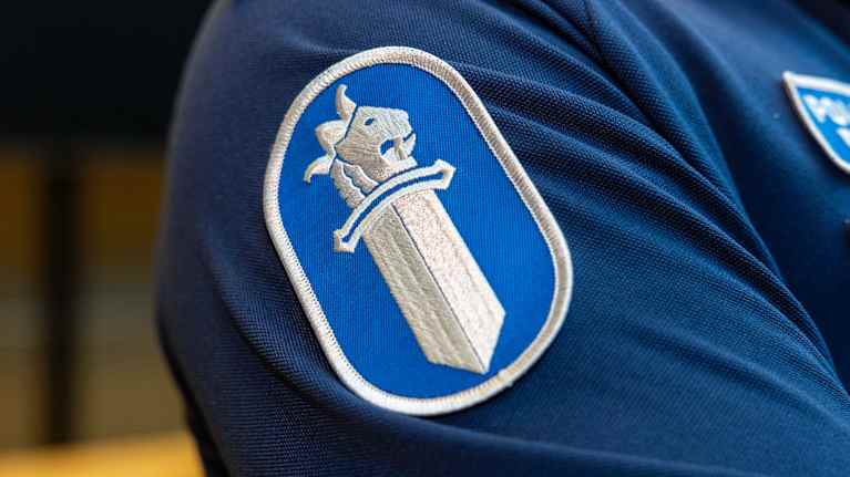 Poliisin tunnuskuva hihamerkkinä poliisin virka-asun olkapään kohdalla.