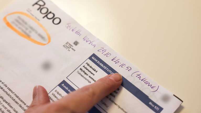 Naisen sormi osoittaa Ropon lähettämän paperilaskun tekstiä.