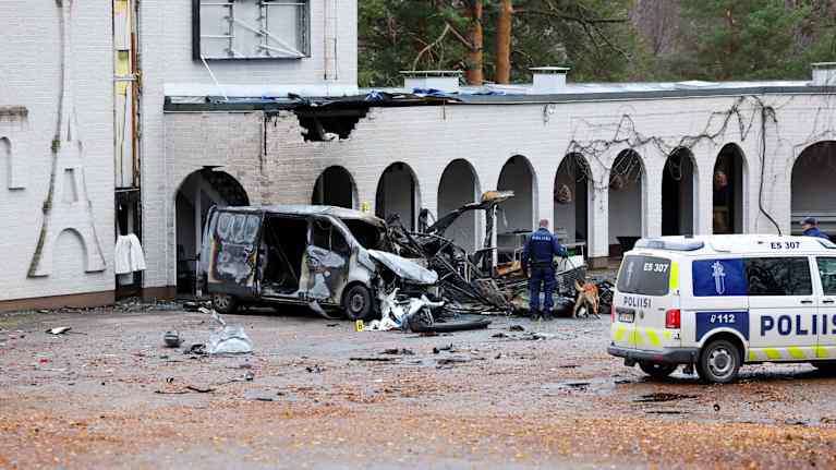 Palanut pakettiauto hotellin edustalla. Paikalla poliisiauto ja poliiseja.