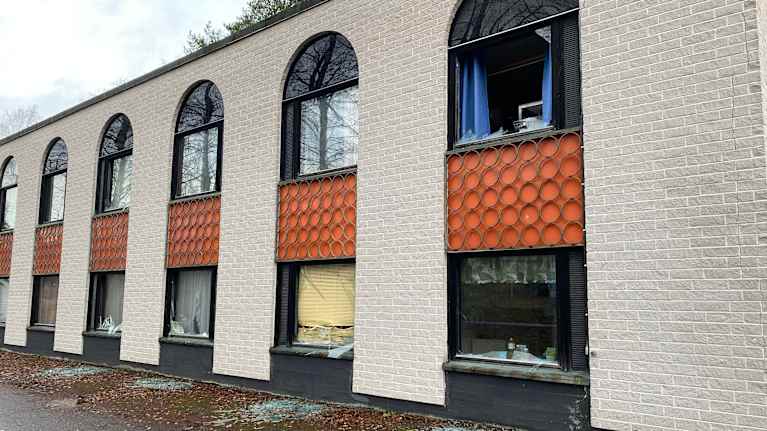 Vaalean rakennuksen ikkunat on rikki, ja kadulle on jäänyt lasinsirpaleita.