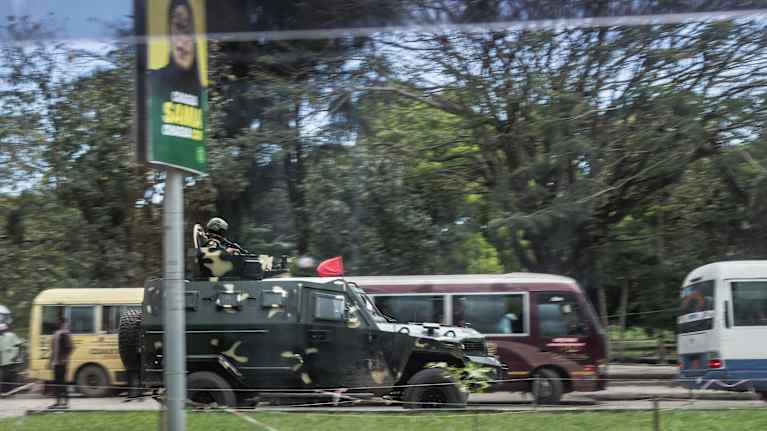 Tansanialaiset sotilaat ajavat Samia Hassanin vaalijulisteen ohi.