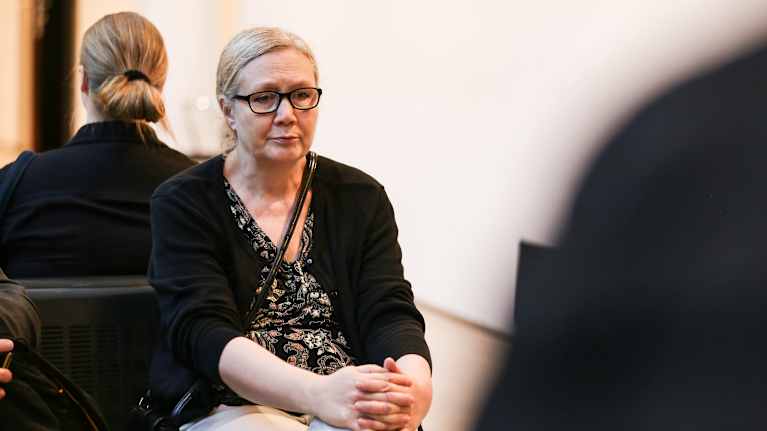 Anneli Auer istuu penkillä Turun oikeustalolla.