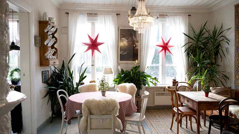 Tunnelmallisesti sisustettu ruokailuhuone, jossa pyöreä pöytä on katettu punavalkoruudullisella liinalla. 