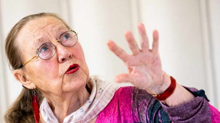 Eläkeläiset Seijaliisa Pekkanen istuu pöydän ääressä jossa akvarellejä ja muita taidevälineitä