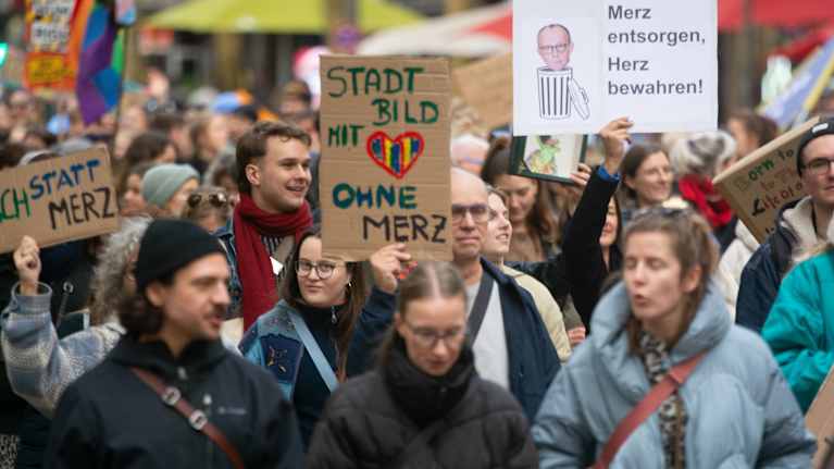 Mielenosoittajia kadulla talvitakeissa. ylteissä lukee esimerkiksi "Stadt Bild mit Herz ohne Merz" ja "Merz entsorgen, Herz bewahren",