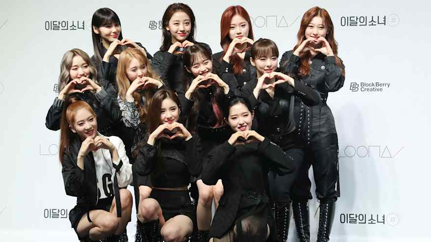 K-Pop -ryhmä Loona poseeraa sydämen muotoisilla käsieleillä lehdistötilaisuudessa.
