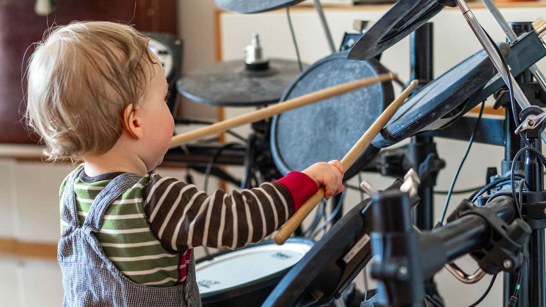 Pieni lapsi soittaa sähkörumpuja innokkaasti.