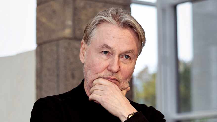 Lähikuva miehestä, joka kuuntelee pohdiskellen pitäen kättä leuassaan.