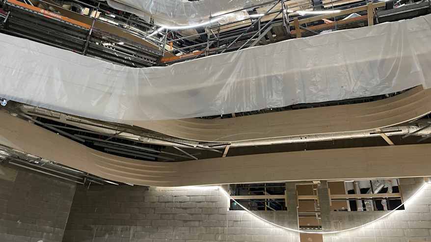 Rakennusvaiheessa olevan Turun musiikkitalo Fuugan puisia rakennelmia seinillä. Kaartuvaa, vaaleaa puuta. 