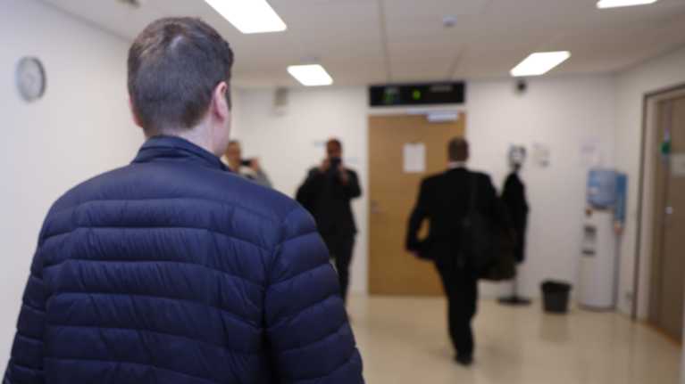 Syytetty kävelee oikeussaliin.