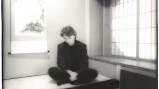 Nuori mies istuu japanilaistyylisessä huoneessa tatamilla.