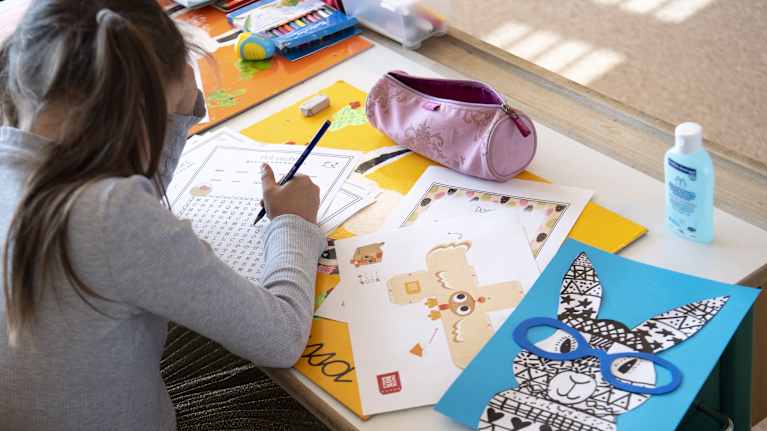 Alakoululaistyttö tekee tehtäviä pulpetin ääressä Sveitsissä.