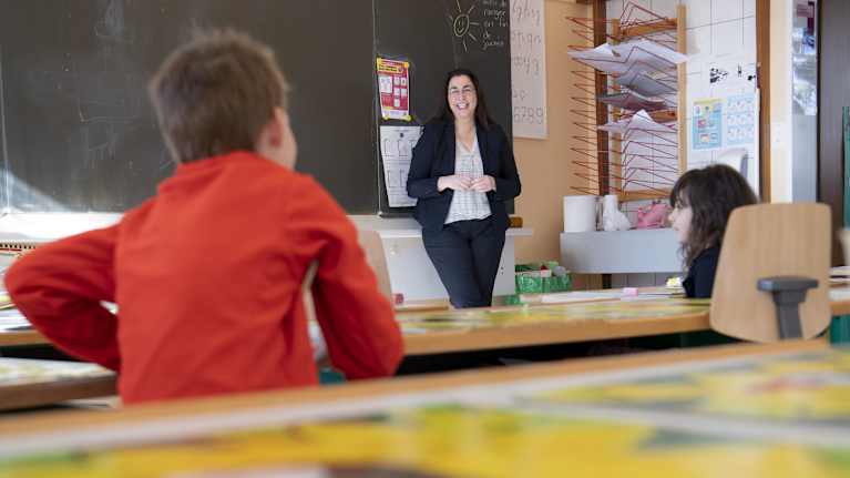 Opettaja ja kaksi oppilasta luokassa Sveitsissä.