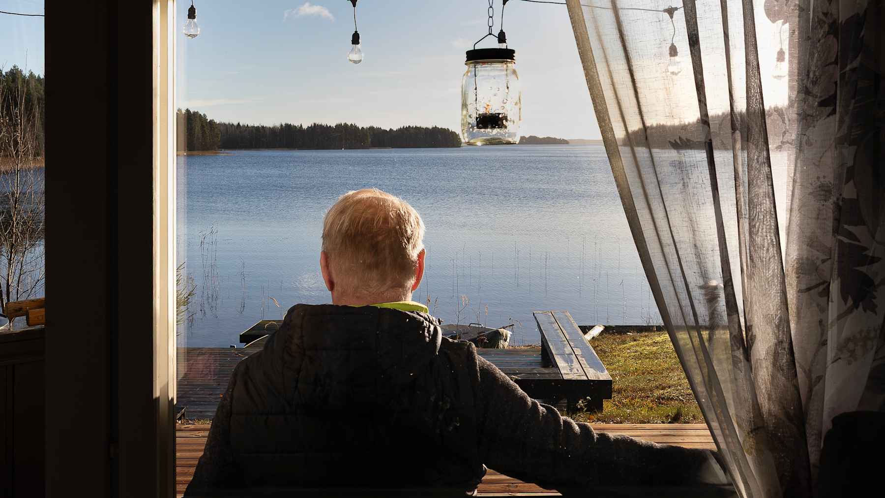 Mies katsoo järvelle saunan kuistilla.