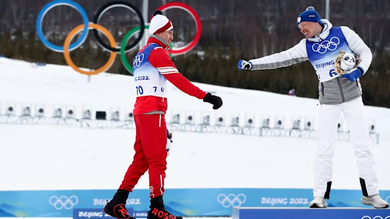 Iivo Niskanen och Aleksandr Bolsjunov interagerar på prispallen under OS i Peking.