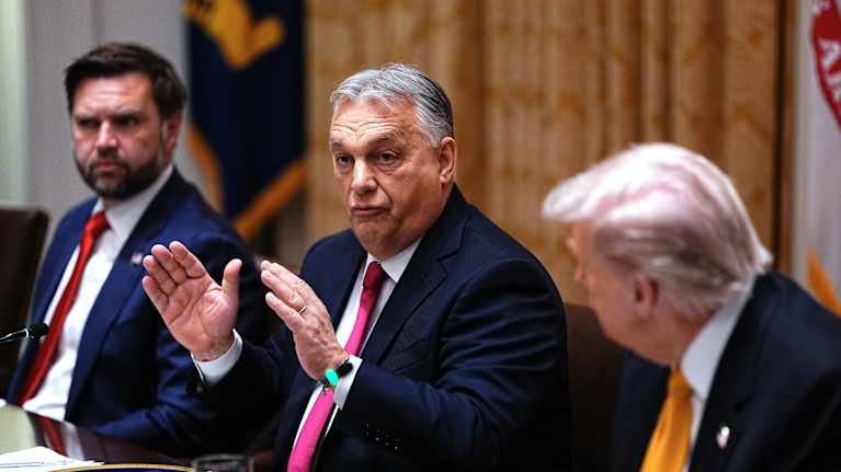 Vance näkyy taustalla, Orban puhuu, viittoo käsillä, Trump kuuntelee. 