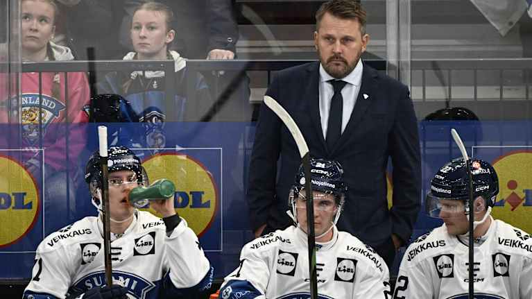 Suomen jääkiekkomaajoukkueen pelaajia ja valmentaja seuraavat ottelua vaihtoaitiossa.